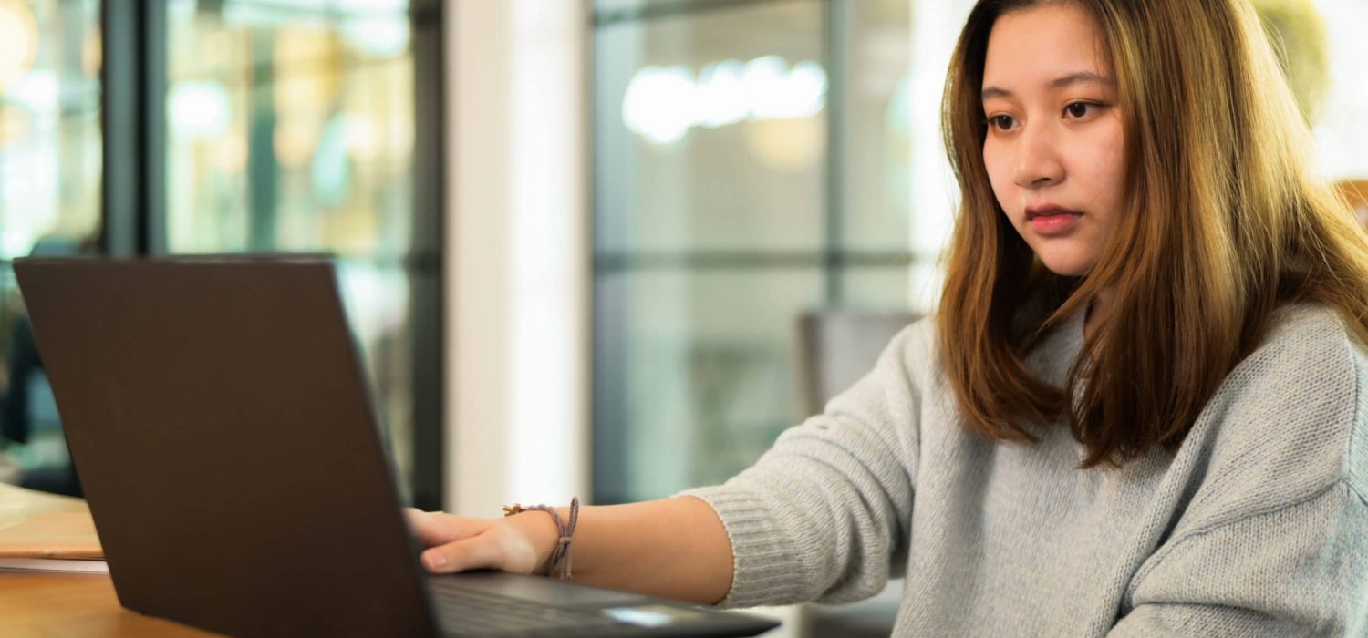 Asian teenage girl using laptop on the desk, online learning, video chat.